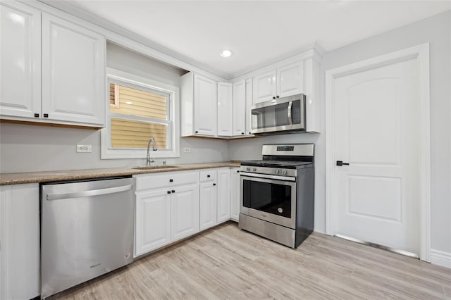 kitchen featuring white cabinets, stainless steel appliances, light hardwood / wood-style floors, and sink