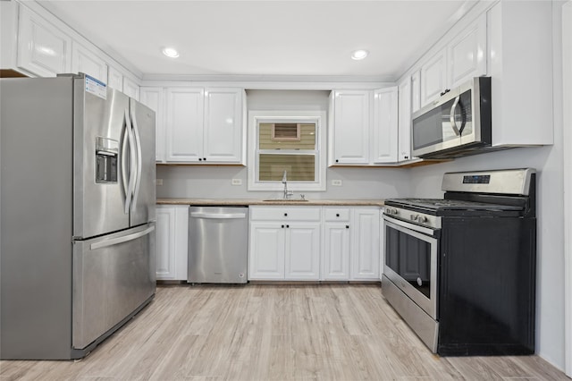 kitchen with white cabinets, sink, light wood-type flooring, and stainless steel appliances