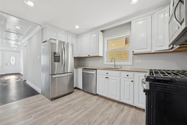 kitchen with white cabinets, stainless steel appliances, light hardwood / wood-style flooring, and sink