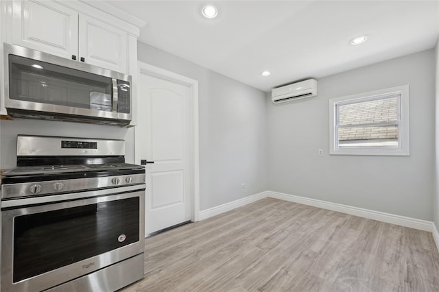 kitchen featuring a wall unit AC, white cabinetry, light hardwood / wood-style flooring, and appliances with stainless steel finishes