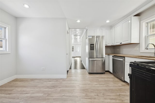 kitchen with white cabinets, plenty of natural light, sink, and stainless steel appliances