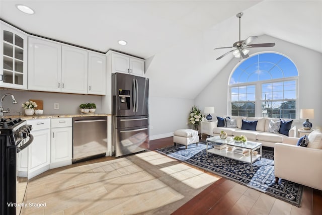 kitchen with white cabinets, lofted ceiling, light wood-type flooring, and appliances with stainless steel finishes