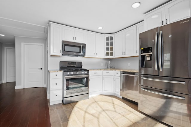 kitchen featuring white cabinets, dark hardwood / wood-style floors, light stone countertops, and stainless steel appliances