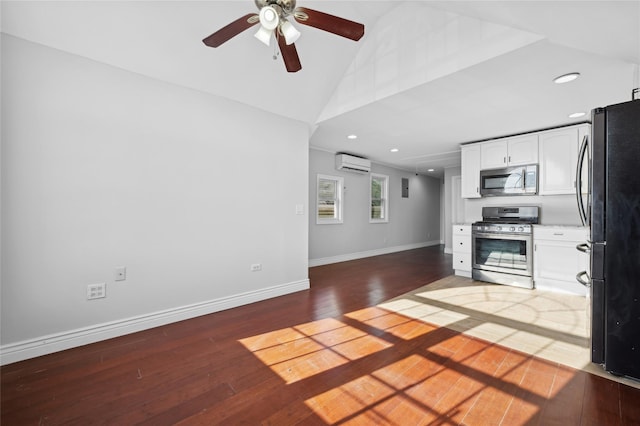 kitchen featuring white cabinetry, a wall mounted AC, hardwood / wood-style floors, vaulted ceiling, and appliances with stainless steel finishes