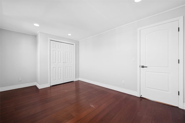 unfurnished bedroom with a closet, dark hardwood / wood-style flooring, and ornamental molding