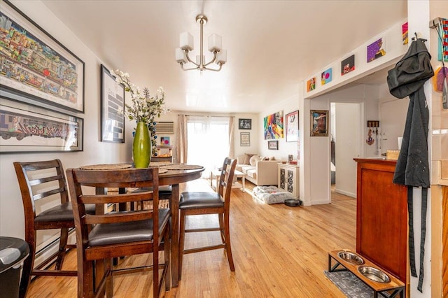 dining area with light hardwood / wood-style floors, baseboard heating, and an inviting chandelier