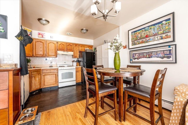 kitchen with tasteful backsplash, black fridge, white range, a notable chandelier, and hardwood / wood-style floors