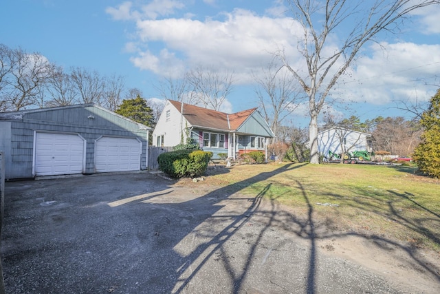 view of front of home featuring covered porch, a front lawn, and a detached garage