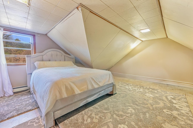 carpeted bedroom featuring lofted ceiling and a baseboard heating unit