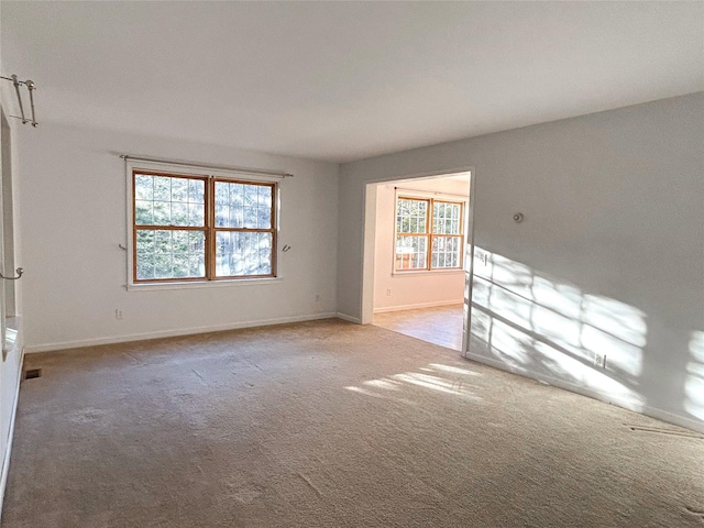 unfurnished room with light colored carpet and a healthy amount of sunlight