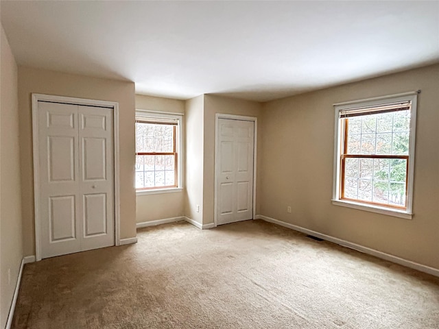 unfurnished bedroom featuring multiple windows and light colored carpet