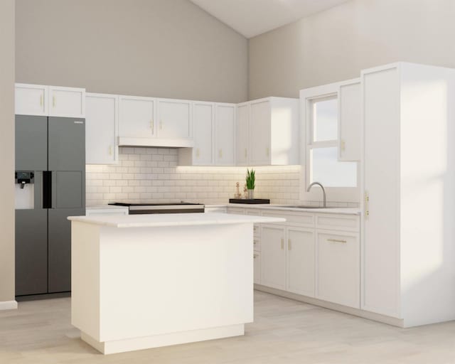 kitchen with white cabinets, a high ceiling, a center island, and stovetop