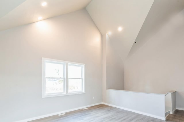 additional living space with high vaulted ceiling and wood-type flooring