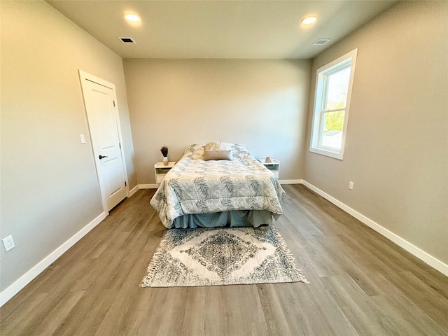 bedroom featuring wood finished floors, visible vents, and baseboards