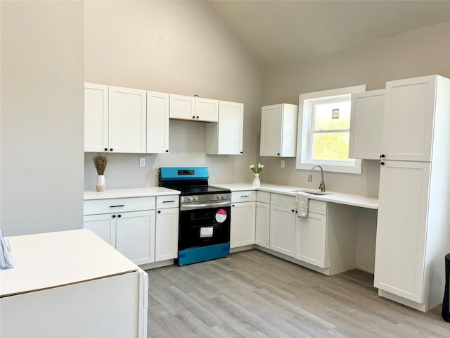 kitchen with light countertops, white cabinets, stainless steel range with electric cooktop, a sink, and light wood-type flooring