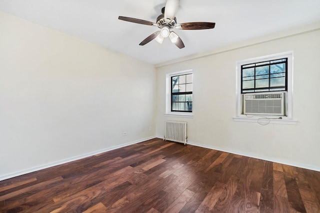 empty room with dark hardwood / wood-style flooring, radiator, a healthy amount of sunlight, and ceiling fan