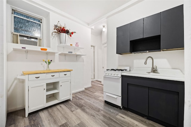 kitchen featuring white gas range, white cabinetry, cooling unit, and light hardwood / wood-style floors