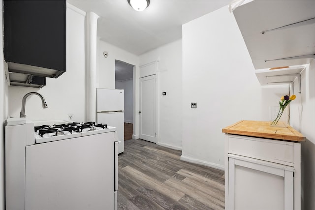 kitchen with white cabinetry, light wood-type flooring, and white appliances