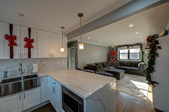 kitchen with white cabinets, light stone countertops, kitchen peninsula, and dark wood-type flooring