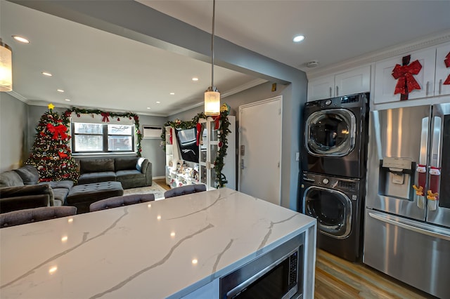 kitchen with stacked washer and clothes dryer, stainless steel fridge with ice dispenser, decorative light fixtures, light stone counters, and white cabinetry