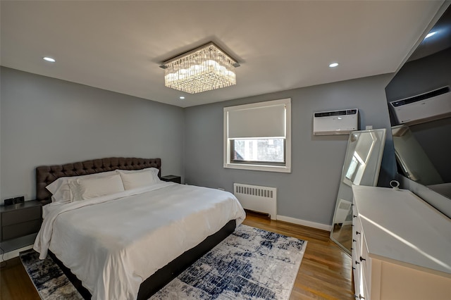 bedroom featuring a wall mounted AC, an inviting chandelier, radiator, and light hardwood / wood-style flooring