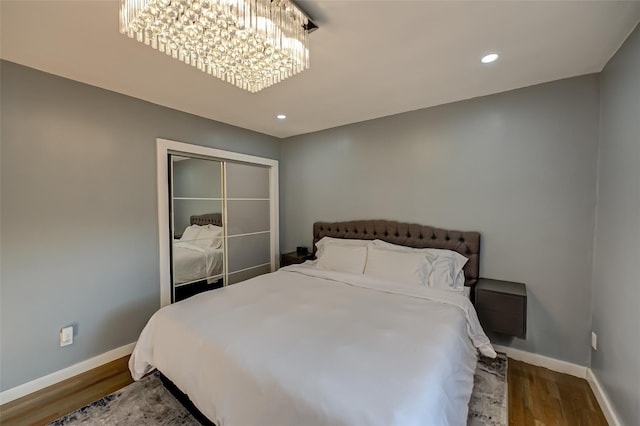 bedroom featuring hardwood / wood-style flooring, a notable chandelier, and a closet