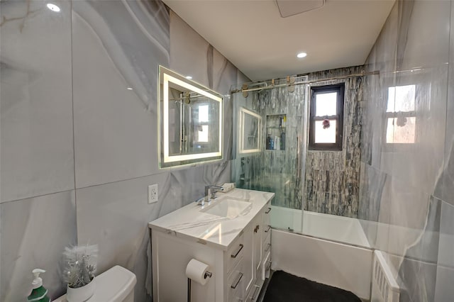 full bathroom with vanity, toilet, shower / bath combination with glass door, and tile walls