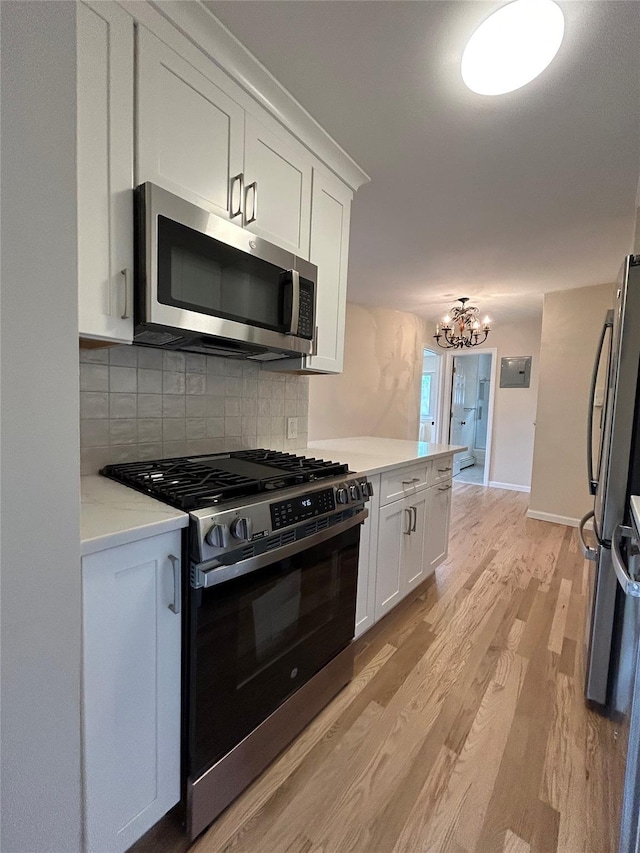 665 Pelham Rd Unit A15, New Rochelle, NY 10805 - kitchen with stainless steel appliances, light wood finished floors, white cabinetry, and a chandelier