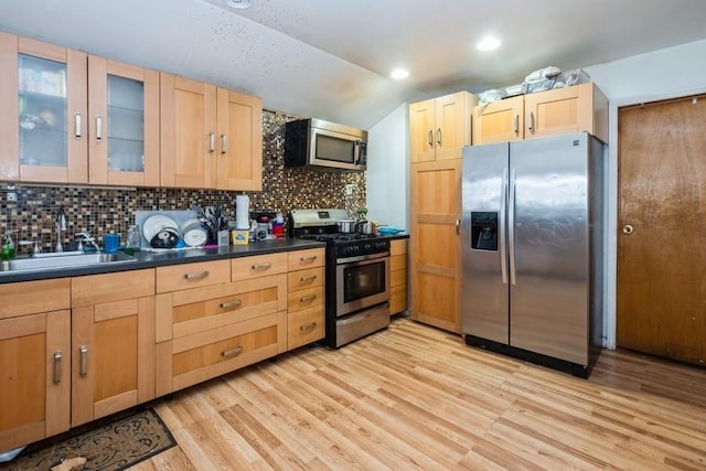 kitchen featuring sink, vaulted ceiling, decorative backsplash, light wood-type flooring, and appliances with stainless steel finishes