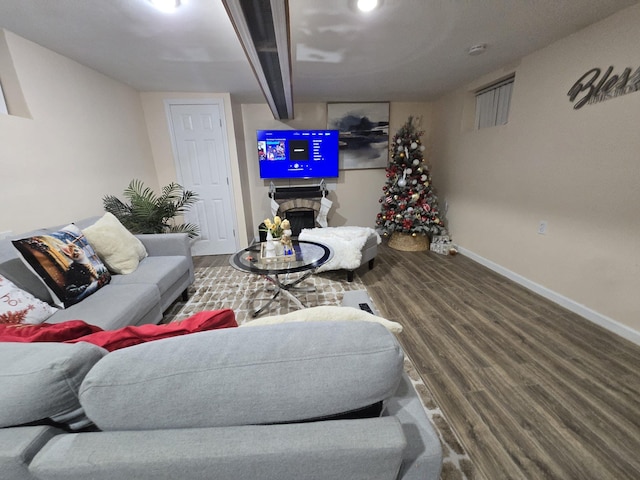 living room featuring a stone fireplace and hardwood / wood-style flooring