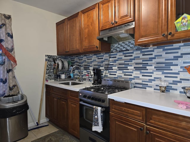 kitchen featuring stainless steel range, decorative backsplash, tile patterned flooring, and sink