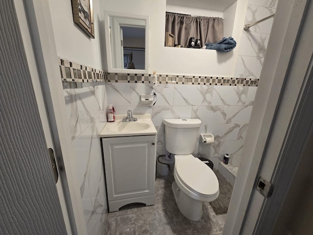 bathroom featuring toilet, vanity, tile walls, and walk in shower