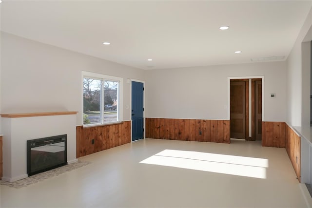 unfurnished living room featuring wooden walls