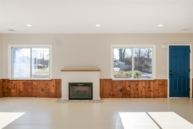 unfurnished living room with plenty of natural light and wooden walls