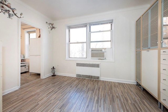 unfurnished bedroom with radiator, cooling unit, and wood-type flooring