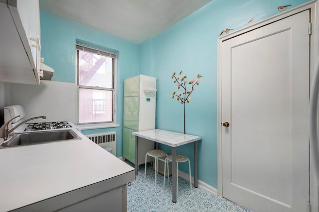 clothes washing area featuring stacked washing maching and dryer, cabinets, radiator heating unit, and sink