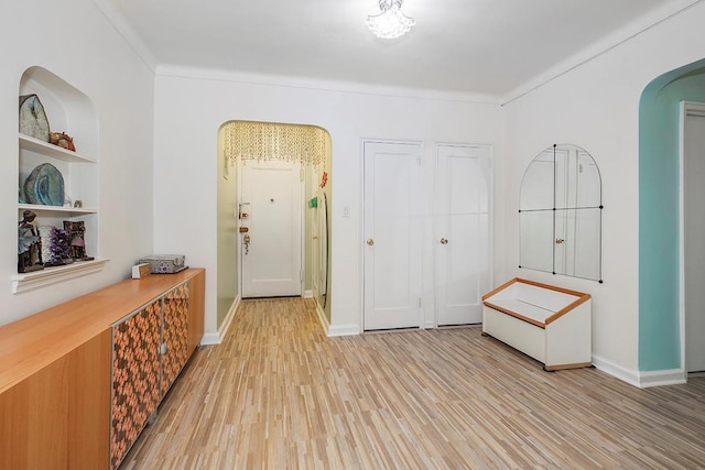 entryway with crown molding and light hardwood / wood-style floors