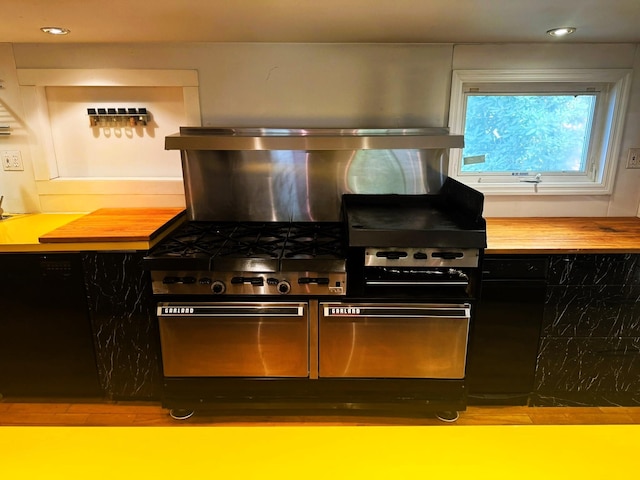 kitchen featuring dishwasher, butcher block countertops, and exhaust hood