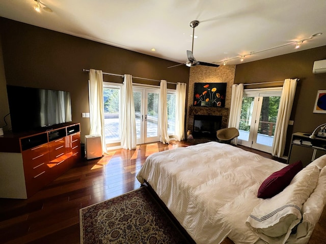 bedroom with access to outside, french doors, hardwood / wood-style flooring, ceiling fan, and a fireplace