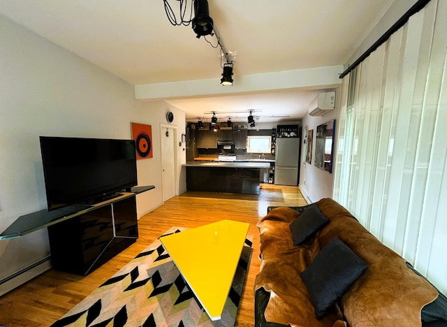 living room with an AC wall unit, light hardwood / wood-style flooring, and a baseboard heating unit