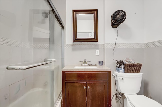 bathroom with vanity, toilet, and tile walls