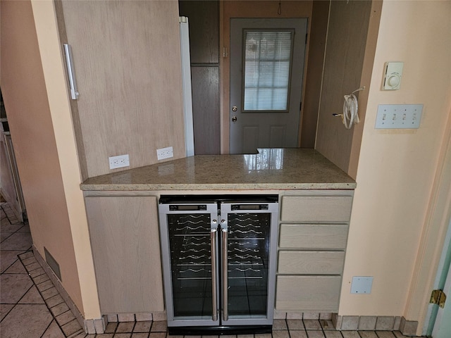 kitchen featuring light stone counters, light tile patterned floors, light brown cabinetry, and beverage cooler