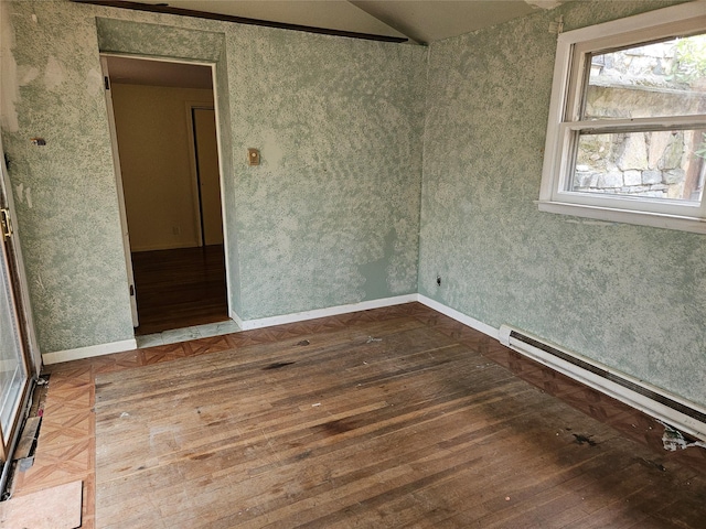 empty room with hardwood / wood-style floors and a baseboard heating unit