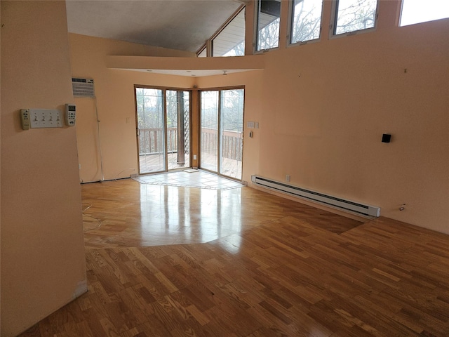 spare room featuring an AC wall unit, light hardwood / wood-style flooring, high vaulted ceiling, and a baseboard radiator