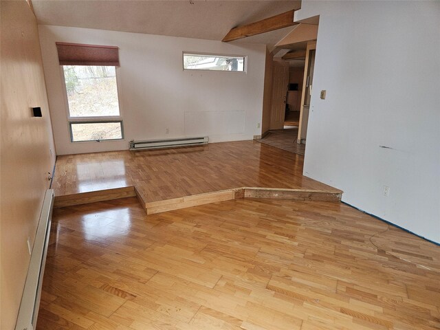 empty room with light wood-type flooring, baseboard heating, and a wealth of natural light