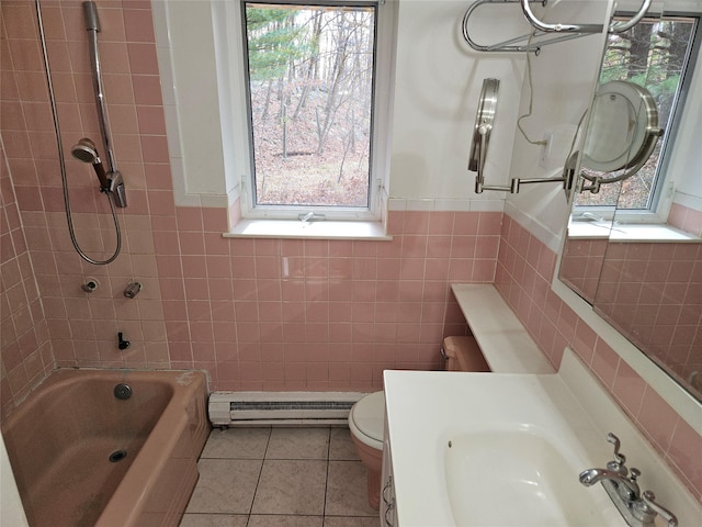 full bathroom featuring a baseboard heating unit, tiled shower / bath, sink, tile patterned flooring, and toilet