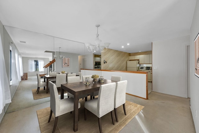 dining space featuring an inviting chandelier and wood walls