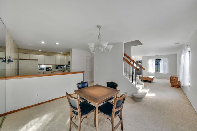 dining room with light carpet and a chandelier