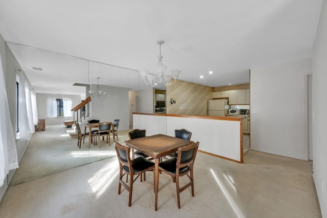 dining area with light colored carpet, an inviting chandelier, and wooden walls