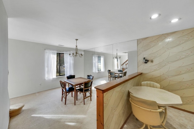 dining area with light colored carpet and a notable chandelier